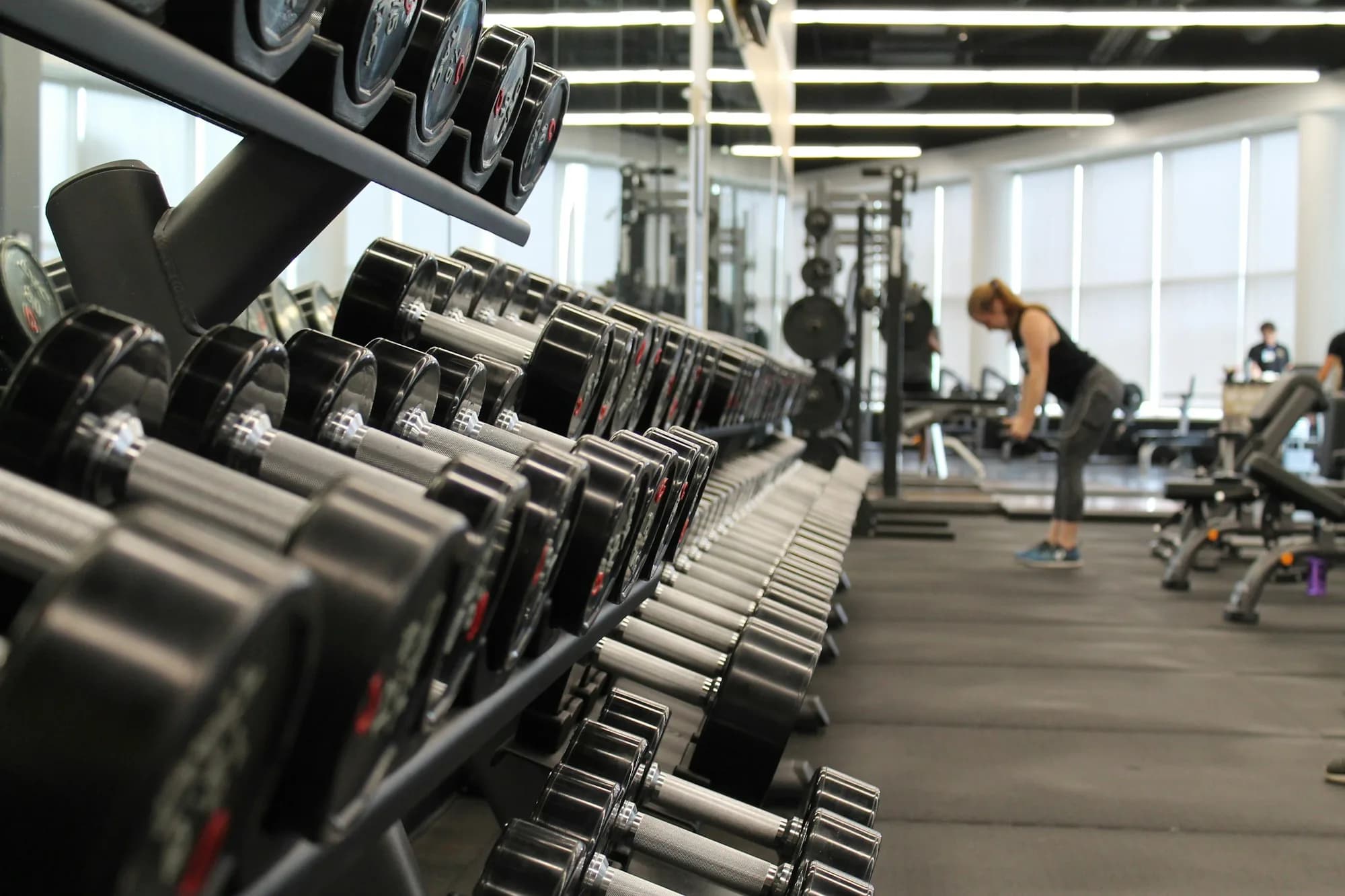 Commercial gym floor with rows of cardio equipment and weight machines